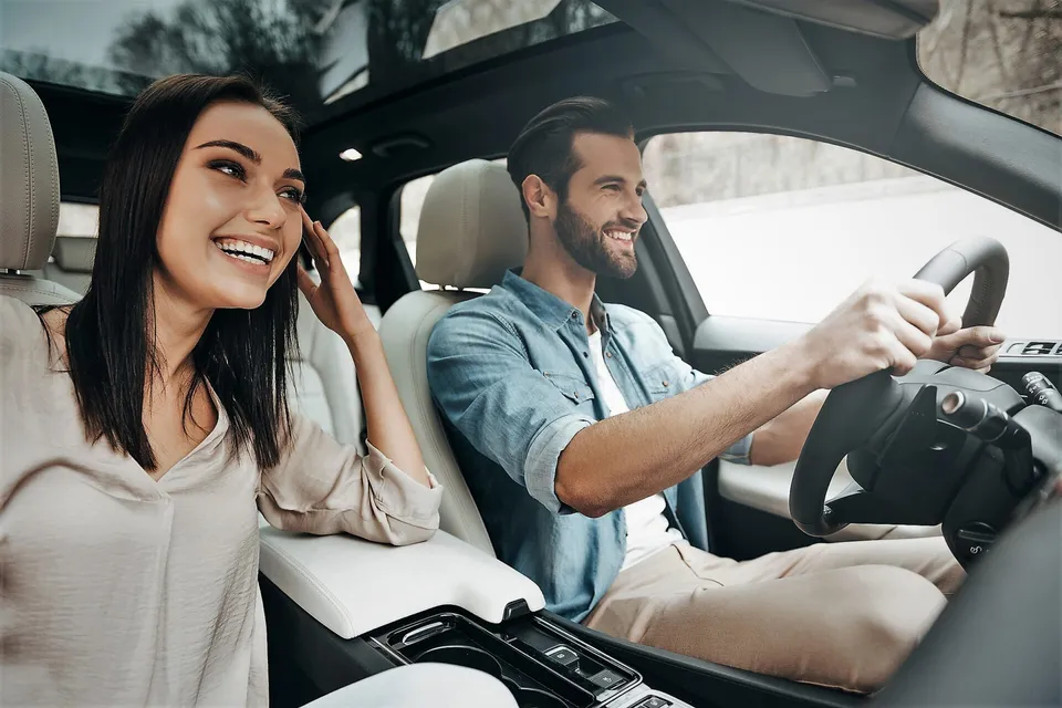 Pareja sonriendo dentro de su auto